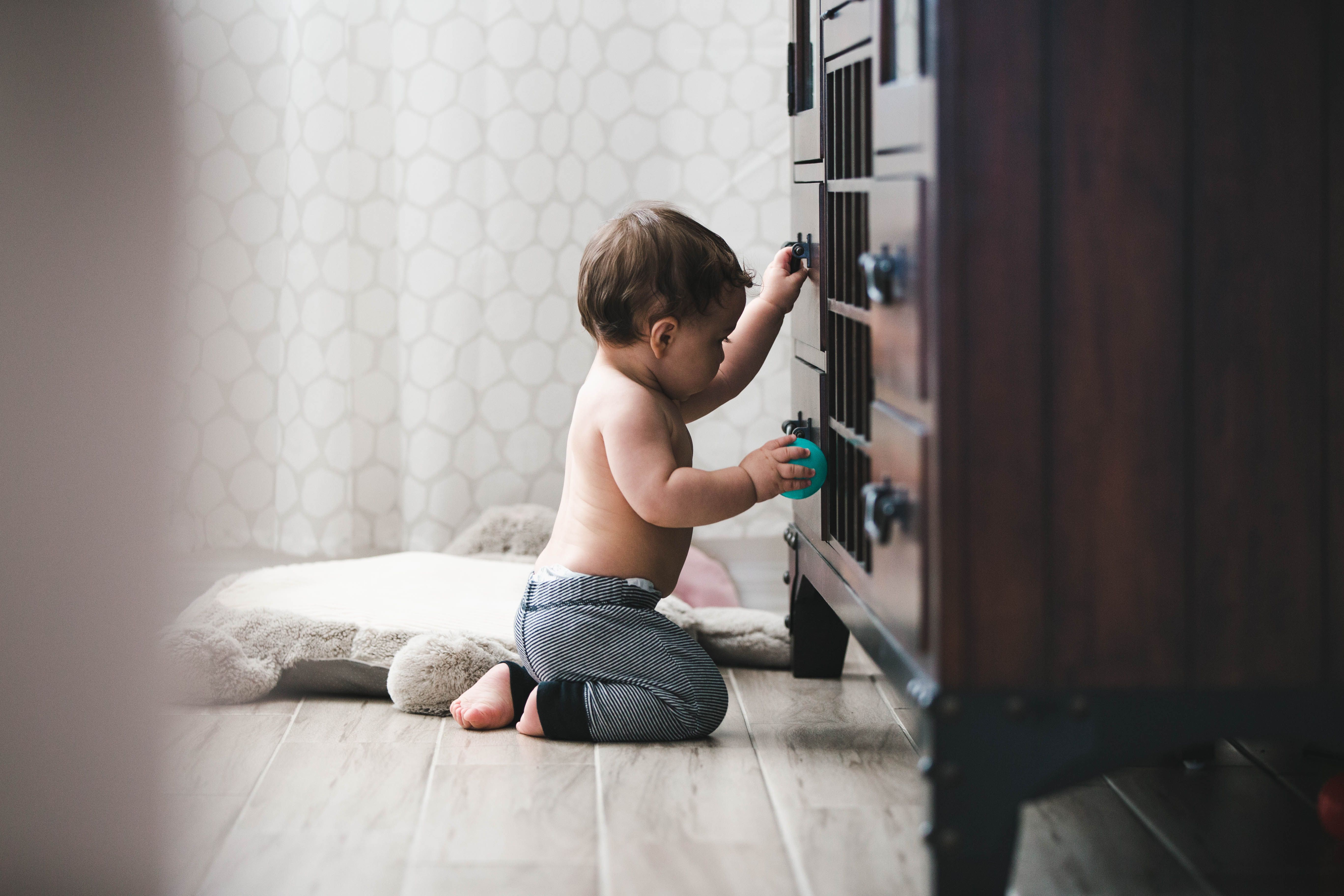 The baby is trying to climb a securely anchored dresser The baby is trying to climb a securely anchored dresser