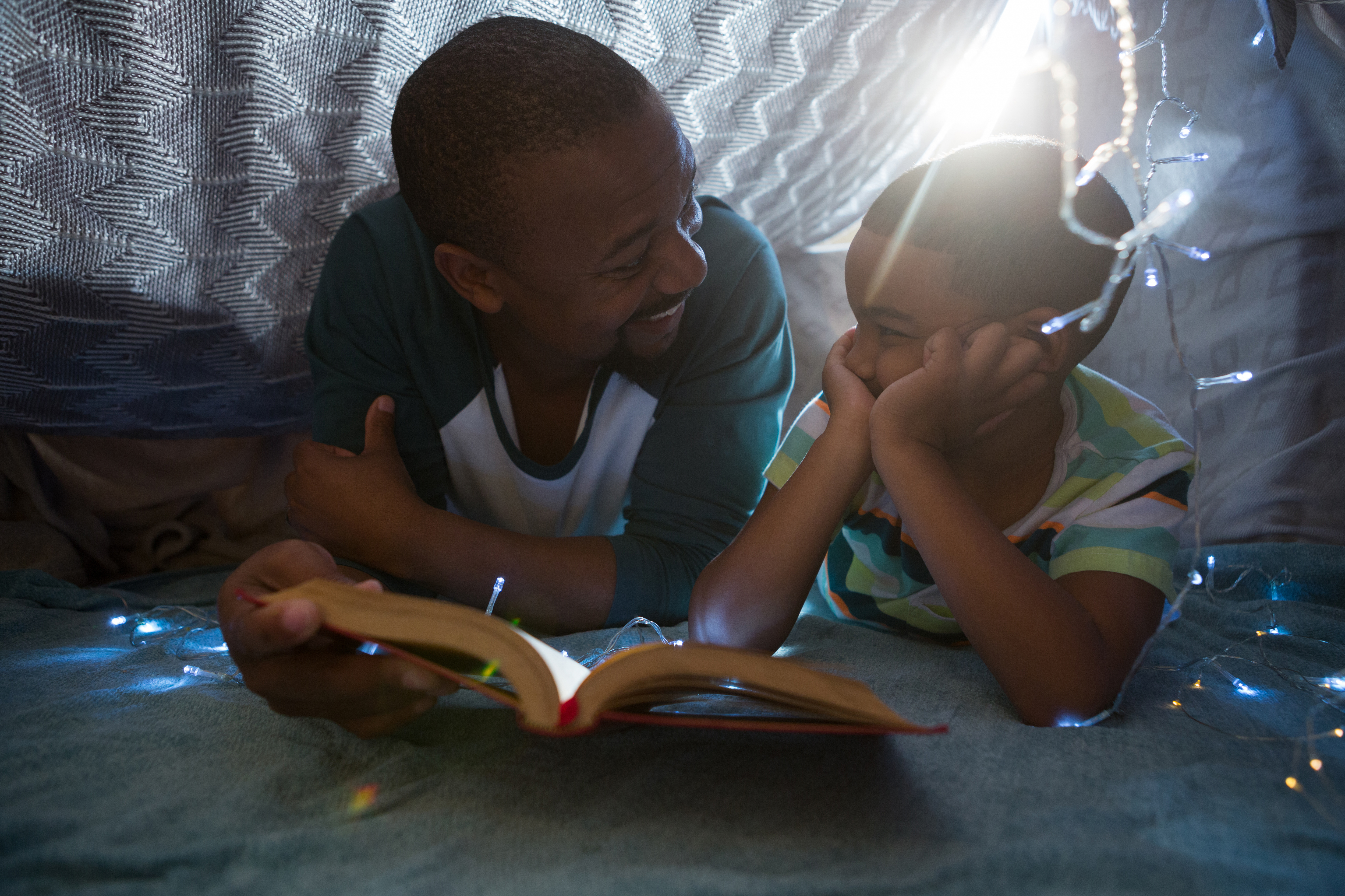 The father reads books to his child to help broaden the child's knowledge and imagination. The father reads books to his child to help broaden the child's knowledge and imagination.