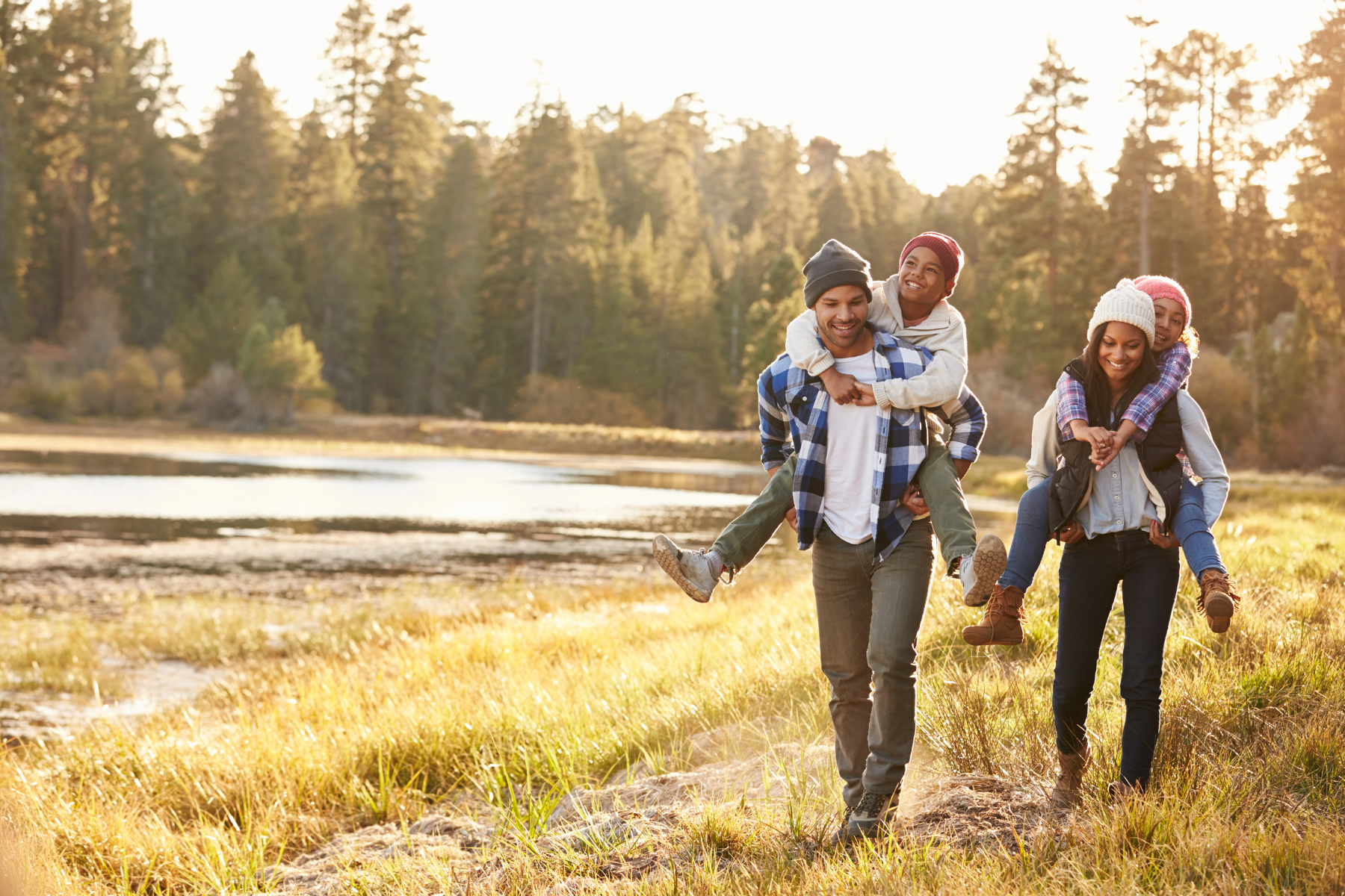 Happy family walking together near a lake in Northern Virginia during fall, with parents giving piggyback rides to kids—showcasing outdoor lifestyle and family-friendly living in the region. Happy family walking together near a lake in Northern Virginia during fall, with parents giving piggyback rides to kids—showcasing outdoor lifestyle and family-friendly living in the region.