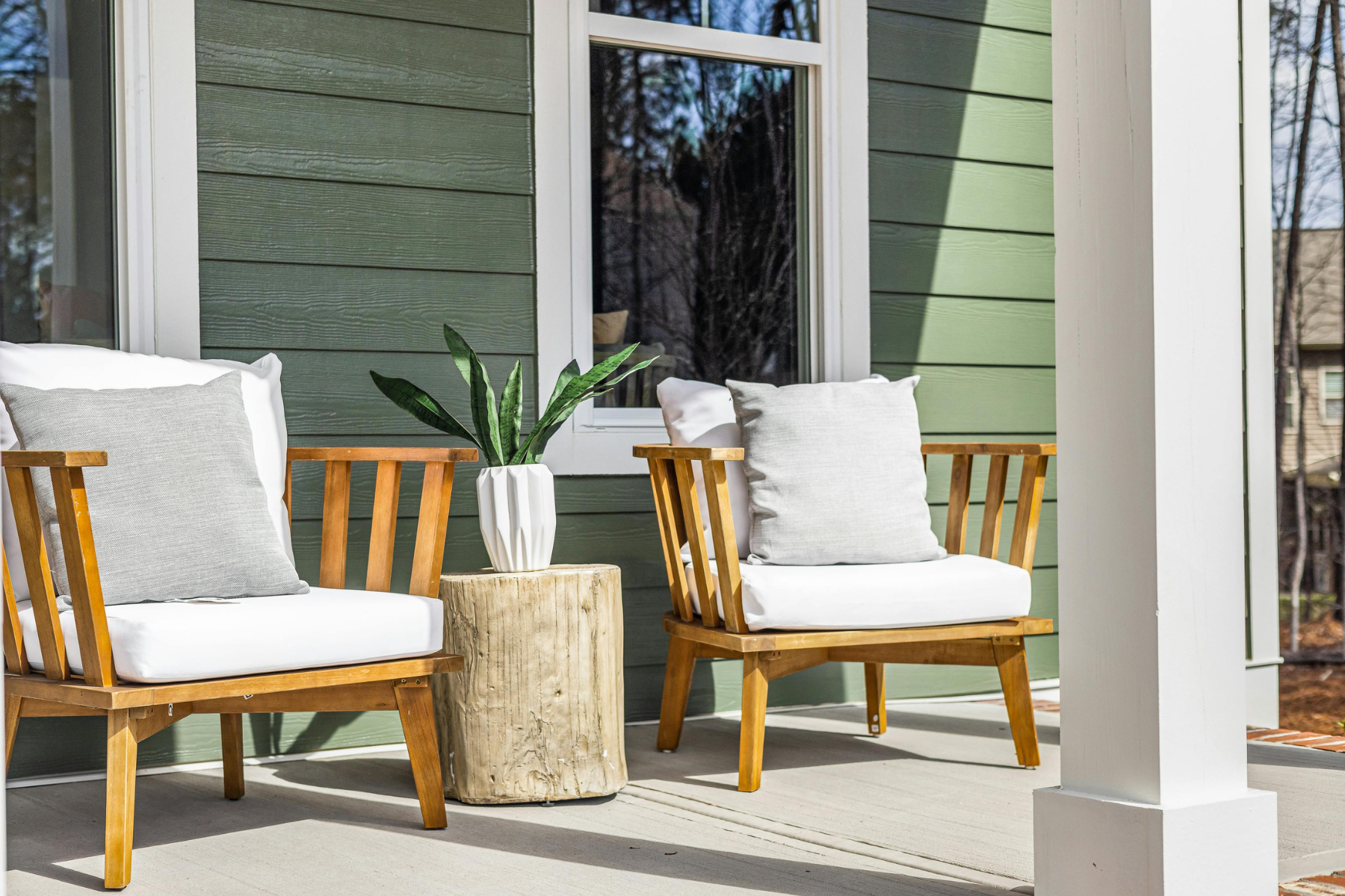 This image features a cozy, staged front porch with modern wooden chairs, plush cushions, and a simple plant—illustrating how creating a welcoming seating area can help buyers emotionally connect with a home. This image features a cozy, staged front porch with modern wooden chairs, plush cushions, and a simple plant—illustrating how creating a welcoming seating area can help buyers emotionally connect with a home.