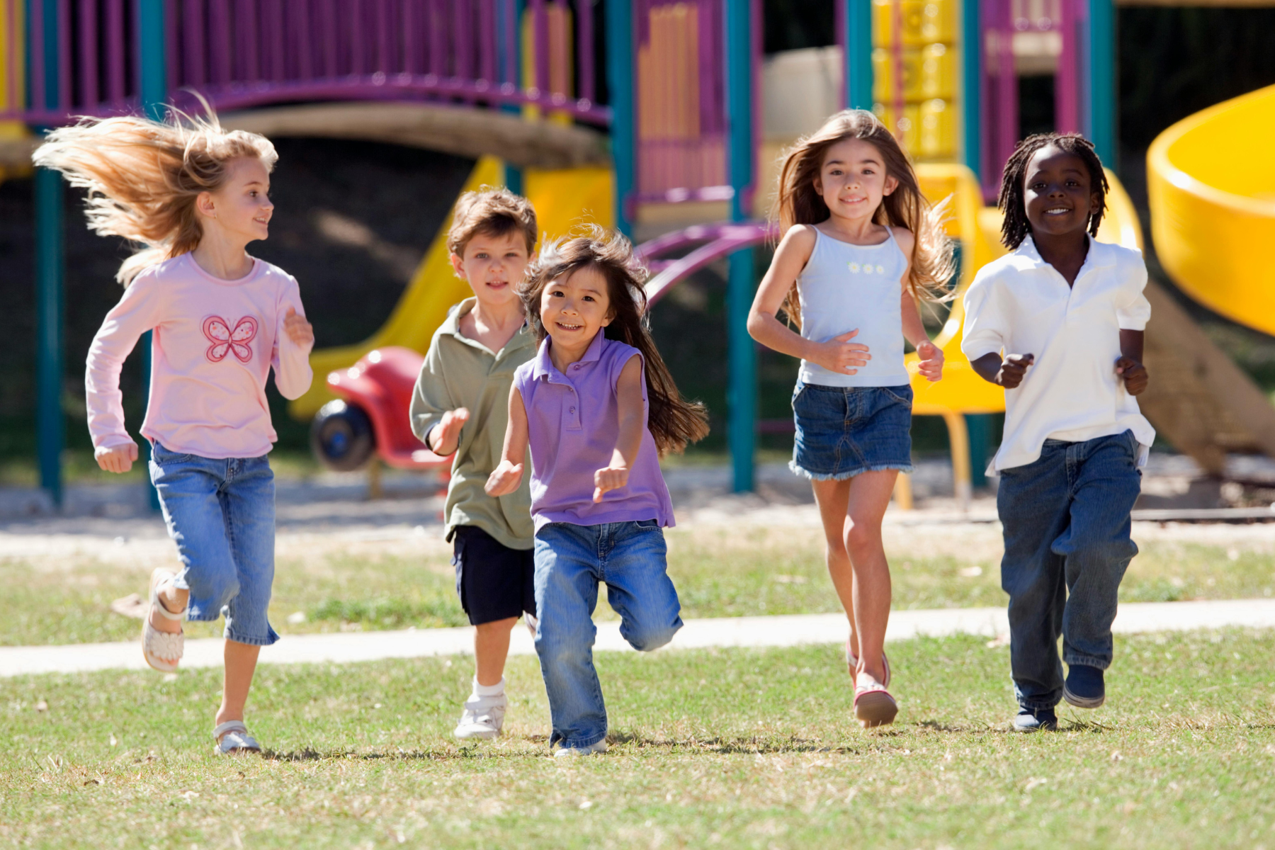 A group of joyful children run toward the camera with big smiles, enjoying a fun-filled day at a colorful playground. A group of joyful children run toward the camera with big smiles, enjoying a fun-filled day at a colorful playground.