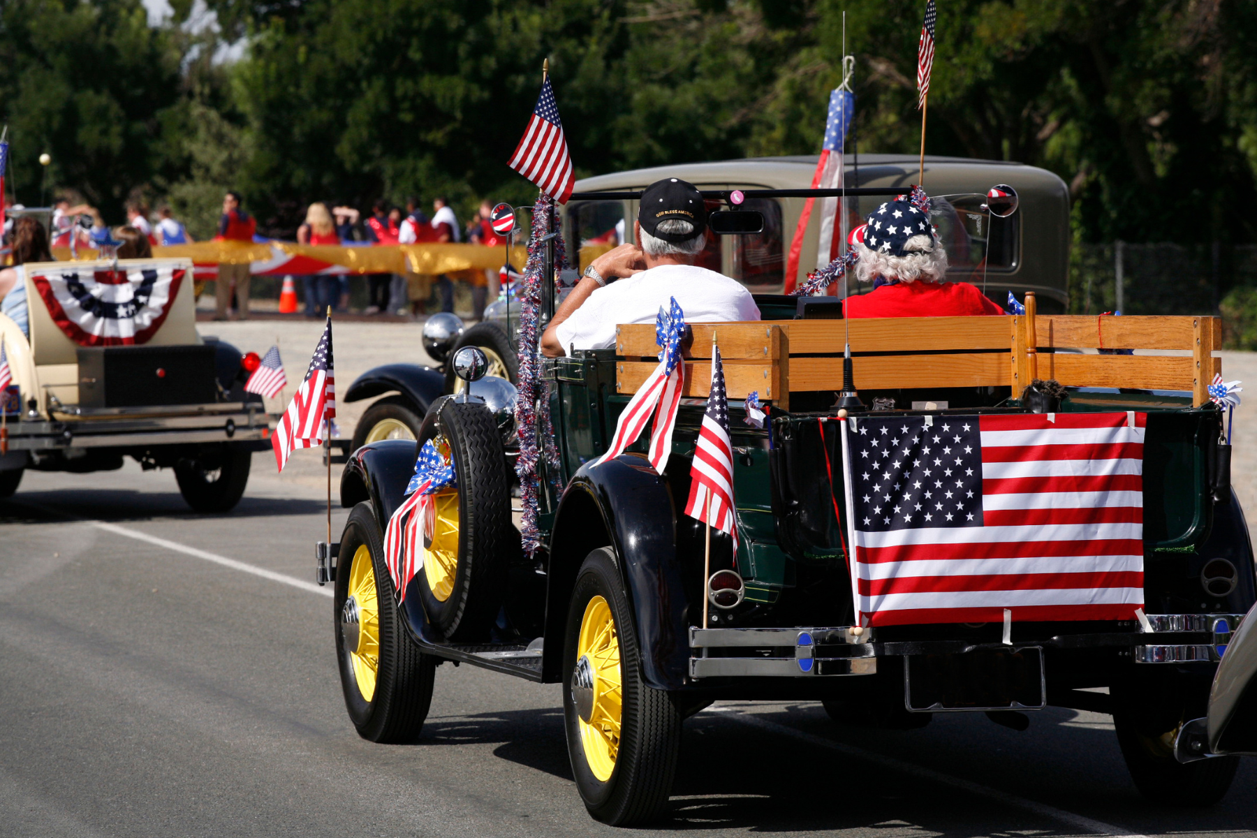 A vintage car decorated with American flags and patriotic bunting drives in a Memorial Day parade, capturing the spirit of community and national pride. A vintage car decorated with American flags and patriotic bunting drives in a Memorial Day parade, capturing the spirit of community and national pride.