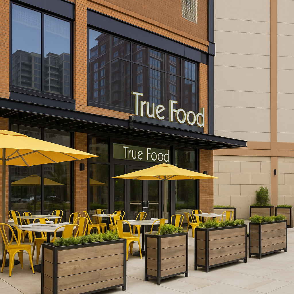 The image shows the vibrant exterior of True Food restaurant, featuring bright yellow chairs and umbrellas, sleek wooden planters, and modern architecture with large glass windows. The image shows the vibrant exterior of True Food restaurant, featuring bright yellow chairs and umbrellas, sleek wooden planters, and modern architecture with large glass windows.