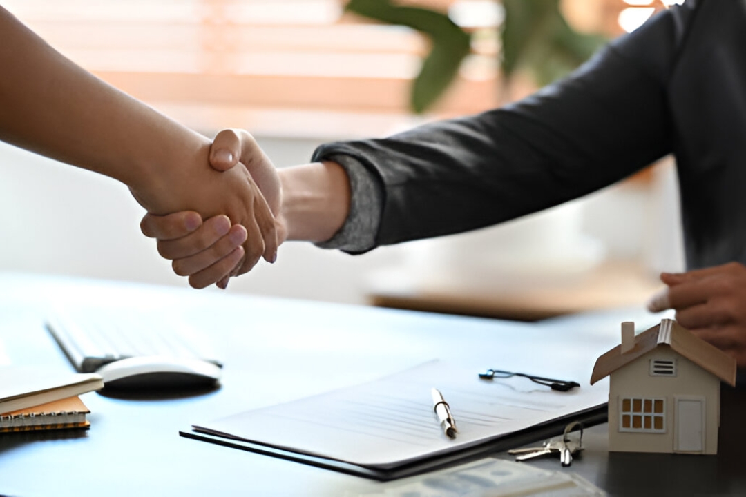 Two business professionals shaking hands over a desk with a house model, representing top real estate investing tools from AMPLIFIREI. Two business professionals shaking hands over a desk with a house model, representing top real estate investing tools from AMPLIFIREI.
