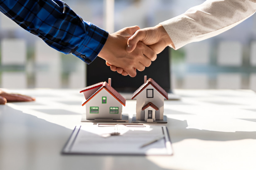 Two hands shaking over small house models and a contract, illustrating AMPLIFIREI's role in SMS marketing for property investors. Two hands shaking over small house models and a contract, illustrating AMPLIFIREI's role in SMS marketing for property investors.
