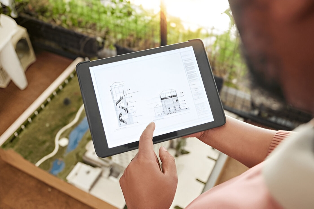 A person examines architectural blueprints on a tablet, showcasing AMPLIFIREI's effective pipeline management software for construction.
