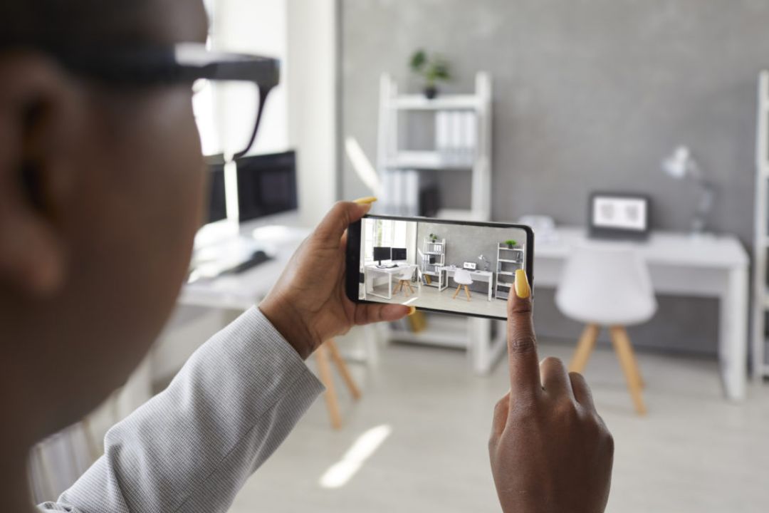 A person holds a phone displaying a virtual tour of an office, showcasing AMPLIFIREI's virtual real estate marketing tools for immersive property experiences. A person holds a phone displaying a virtual tour of an office, showcasing AMPLIFIREI's virtual real estate marketing tools for immersive property experiences.