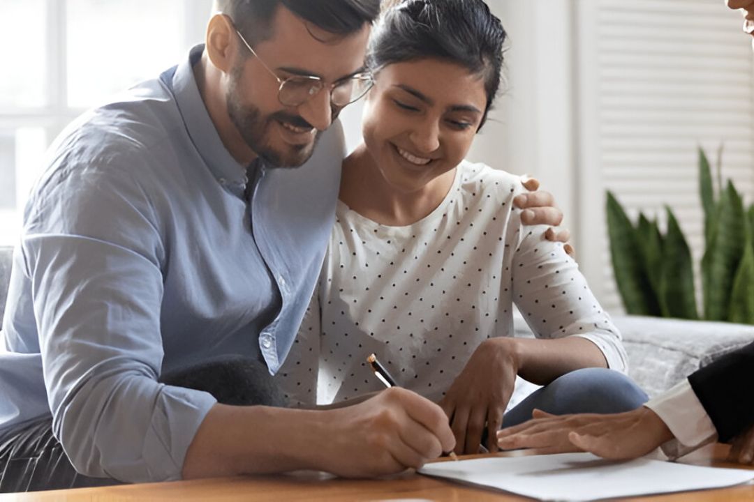 A couple happily signs a document at a table, representing the ease of tracking deal flow in REI CRM provided by AMPLIFIREI. A couple happily signs a document at a table, representing the ease of tracking deal flow in REI CRM provided by AMPLIFIREI.