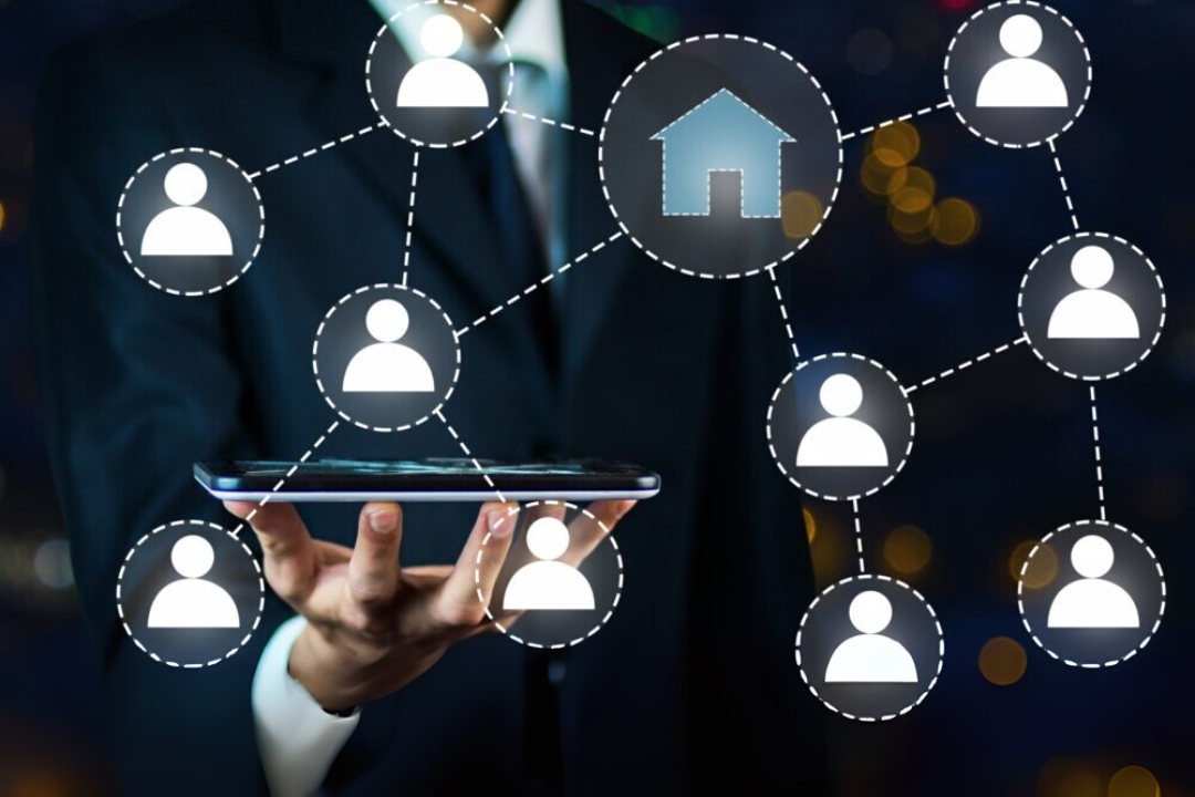 A man holds a tablet with a network of icons, including a house and people, representing AMPLIFIREI's AI-driven REI marketing platforms. A man holds a tablet with a network of icons, including a house and people, representing AMPLIFIREI's AI-driven REI marketing platforms.