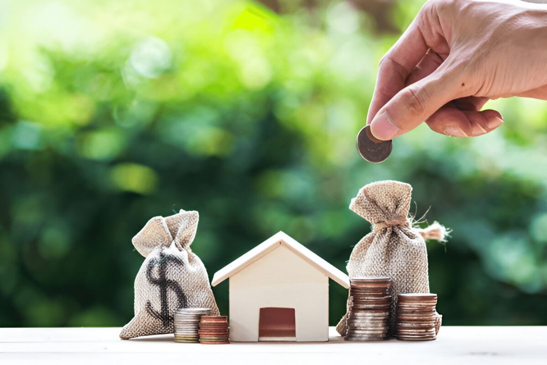 A woman smiles while holding a small house and keys, with a laptop on her desk. She knows the follow-up timing for investor leads. A woman smiles while holding a small house and keys, with a laptop on her desk. She knows the follow-up timing for investor leads.