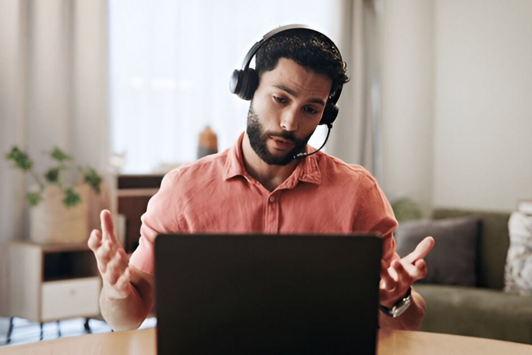A focused man with a headset gestures at his laptop, discussing follow-up timing for investor leads with AMPLIFIREI. A focused man with a headset gestures at his laptop, discussing follow-up timing for investor leads with AMPLIFIREI.