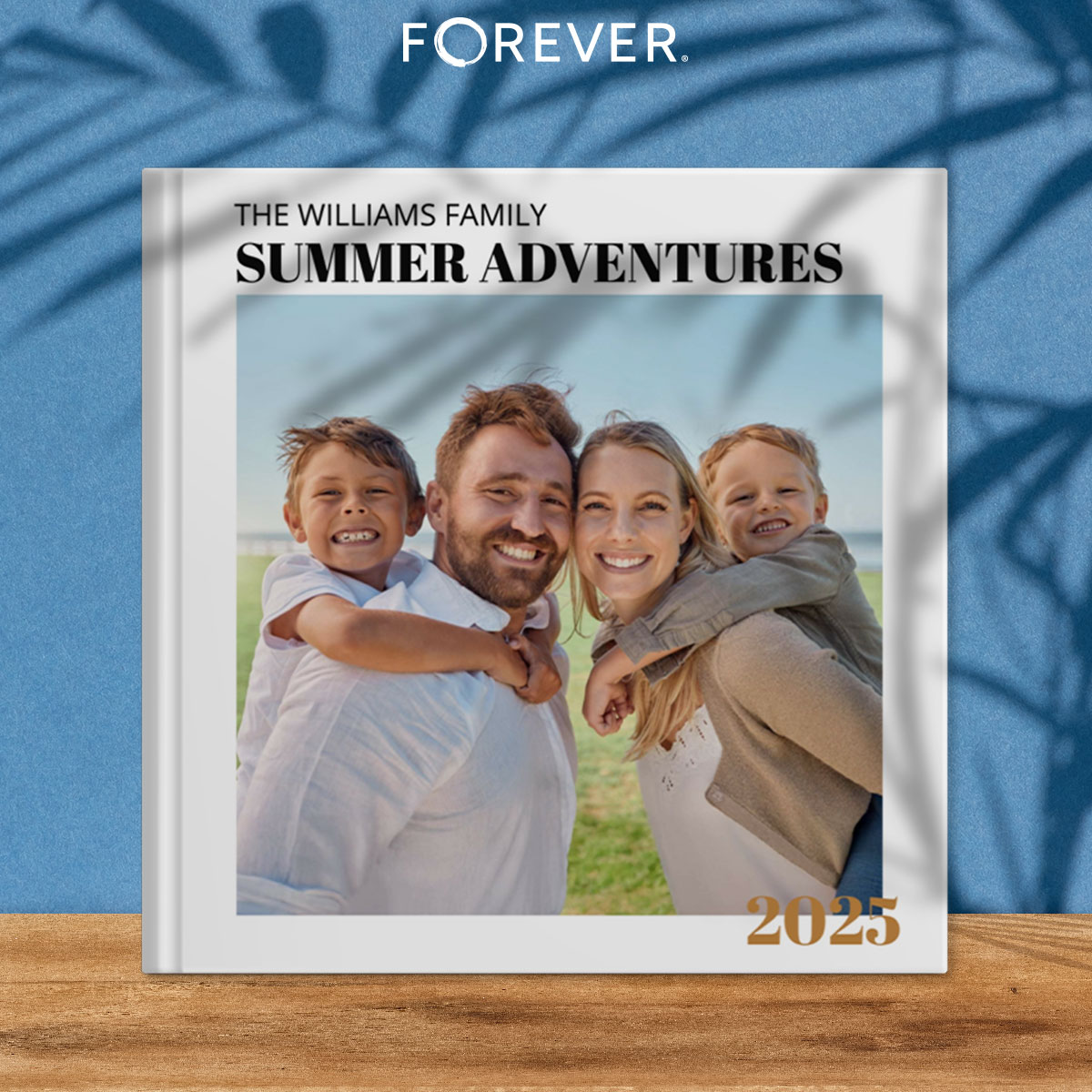 A hardcover photo book titled “The Williams Family Summer Adventures 2025” featuring a smiling family of four, with two young boys on their parents’ backs, standing outdoors on a sunny day.
