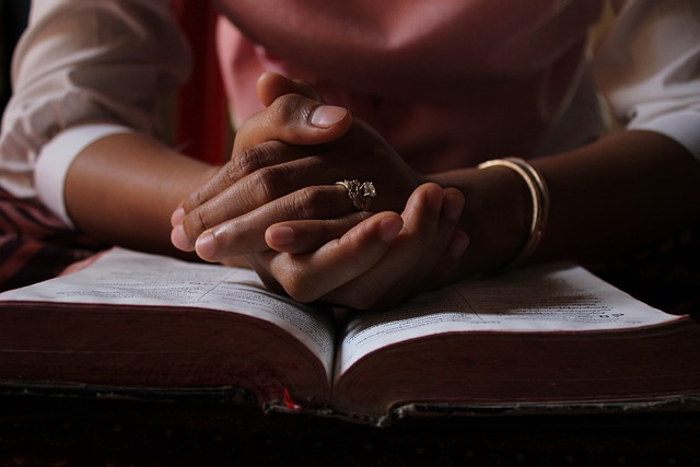 A person holding an open Bible, praying for strength to forgive someone who hurt them. A person holding an open Bible, praying for strength to forgive someone who hurt them.