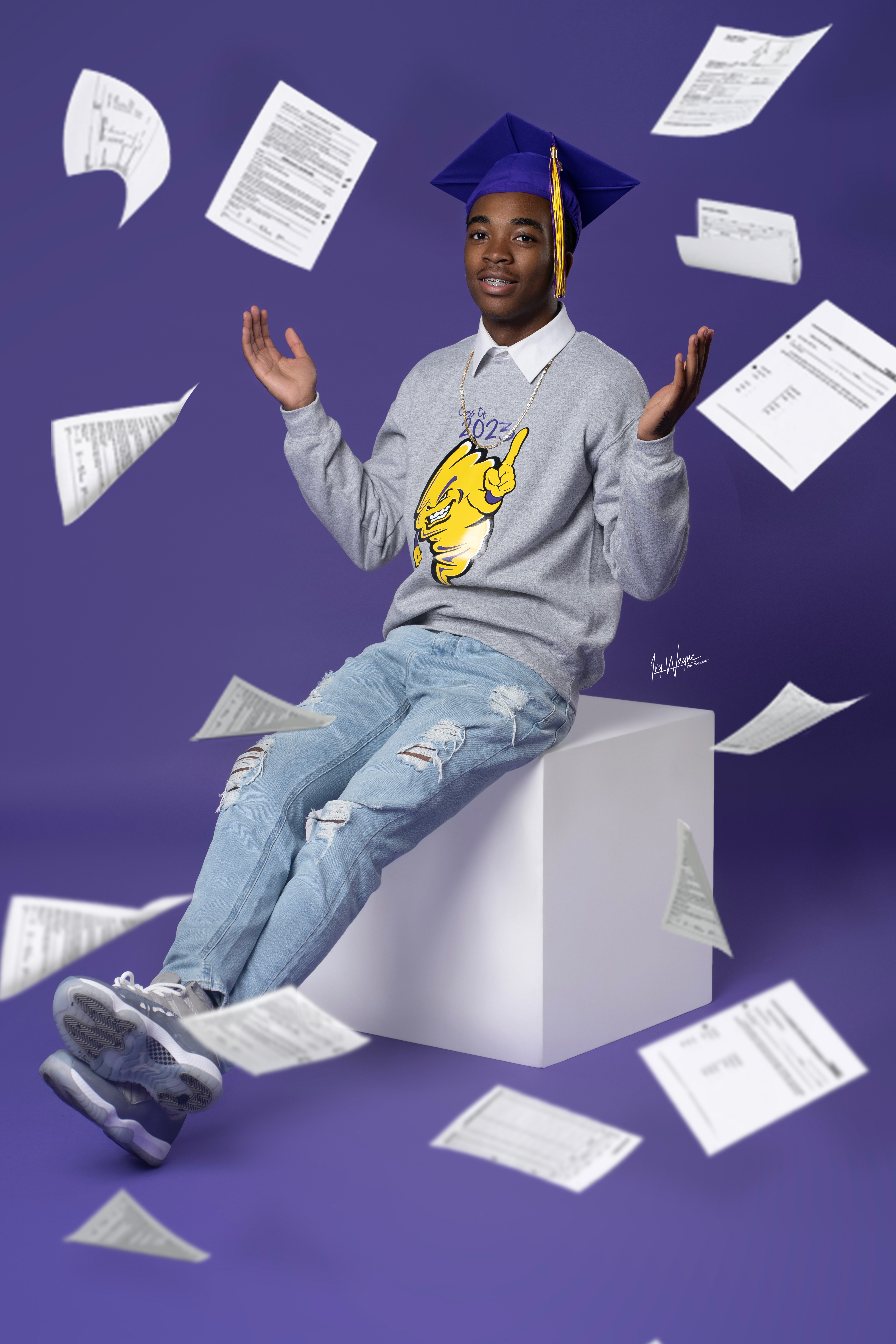 Graduate on purple backdrop with flying papers