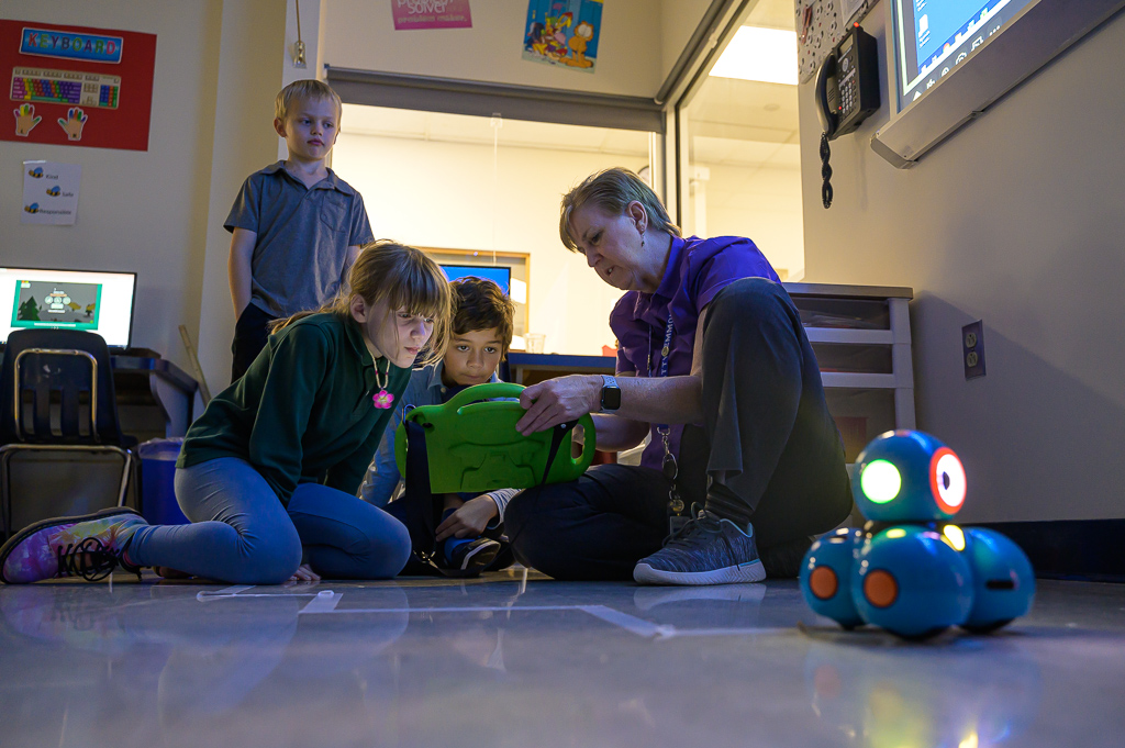 Teacher and two students programming a robot to follow a specific path. Teacher and two students programming a robot to follow a specific path.