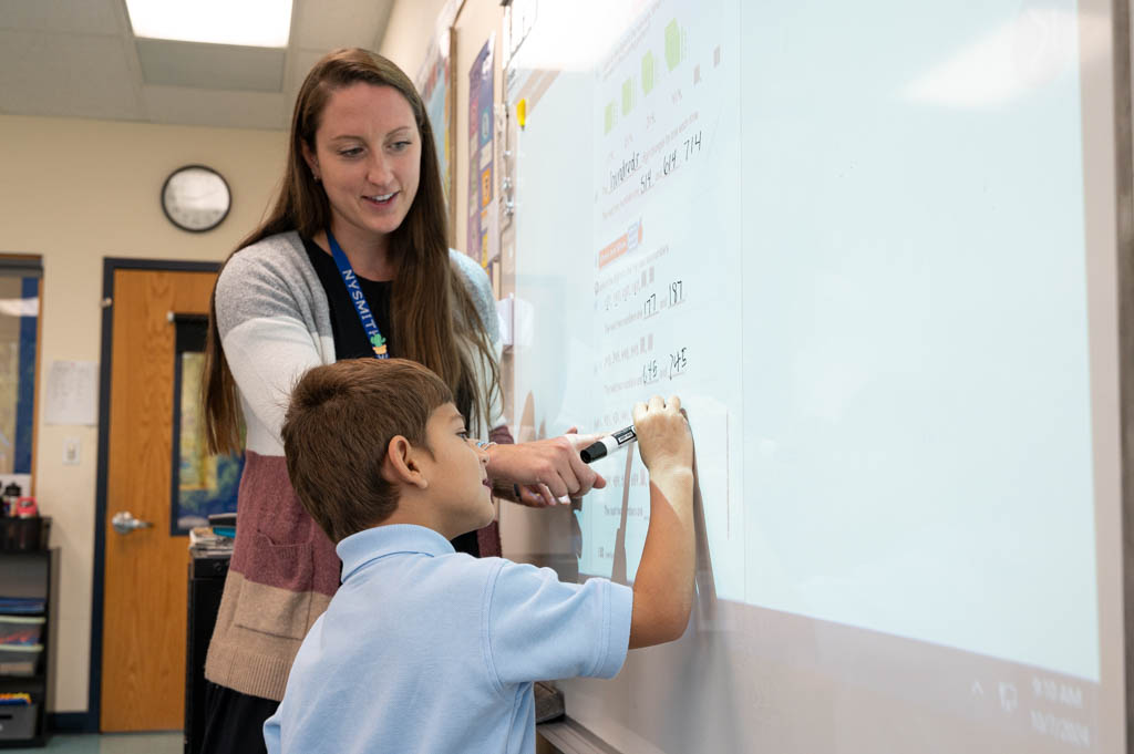 A teacher helping a student fix their error while solving a math equation. A teacher helping a student fix their error while solving a math equation.