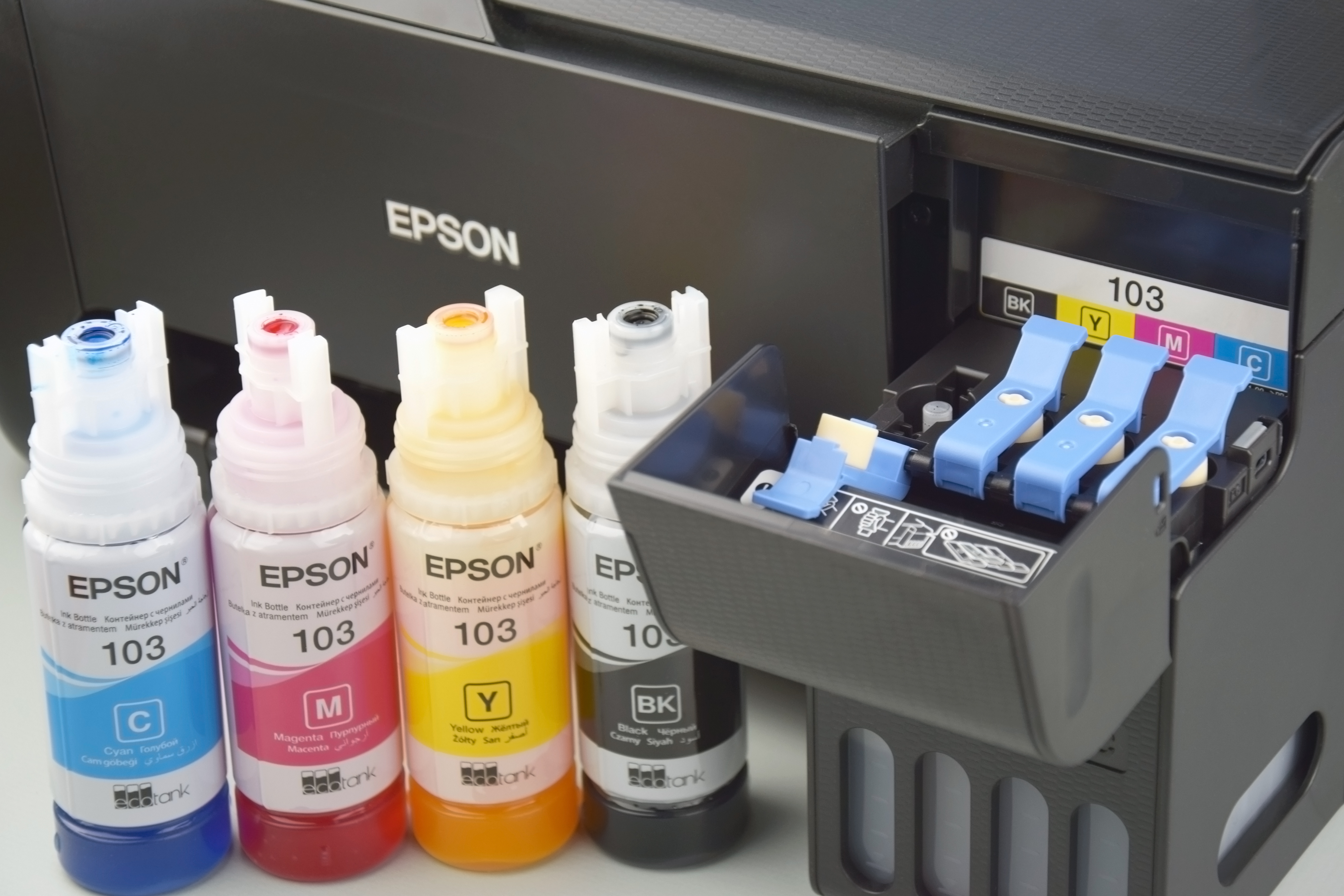 KHARKIV, UKRAINE - FEBRUARY 11, 2023: Four bottles of ink Epson, yellow, red, blue, black, built-in to the Epson L3150 series printer. KHARKIV, UKRAINE - FEBRUARY 11, 2023: Four bottles of ink Epson, yellow, red, blue, black, built-in to the Epson L3150 series printer.