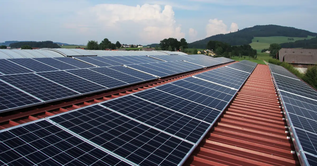 Commercial roof-mounted solar panels with a hill view in the background.  