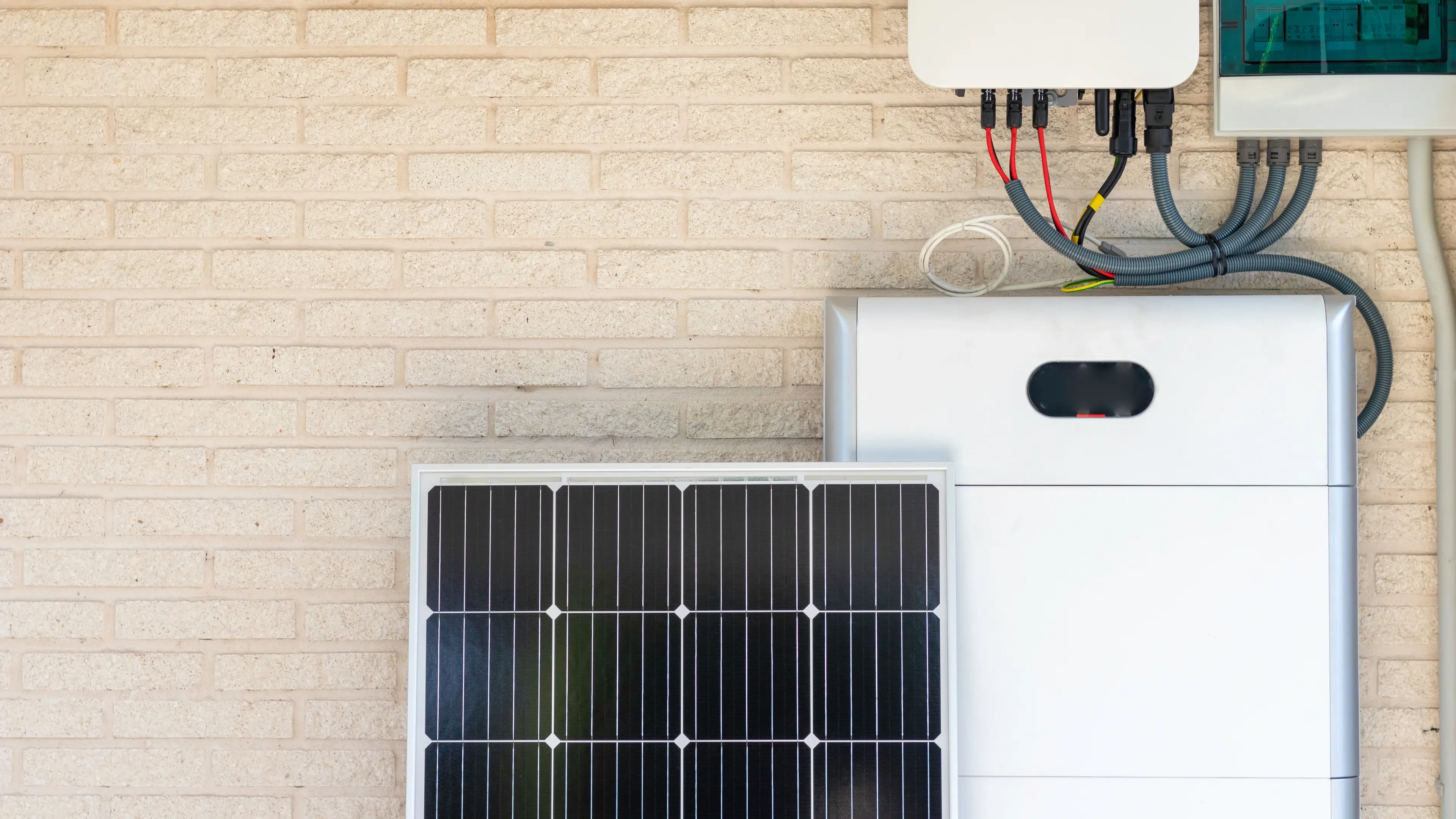 A solar panel next to a solar battery mounted and installed on a wall, illustrating renewable energy storage.  