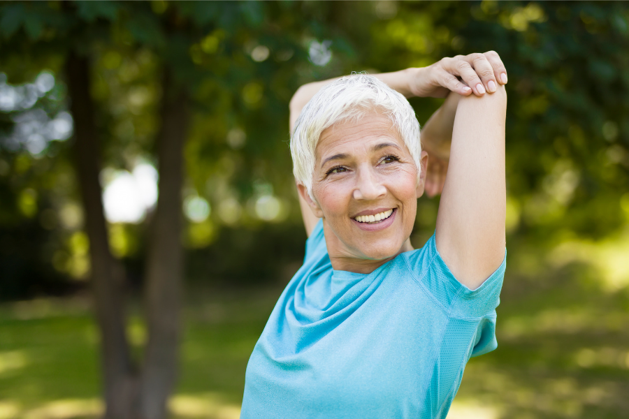 woman with silver hair stretching her shoulder