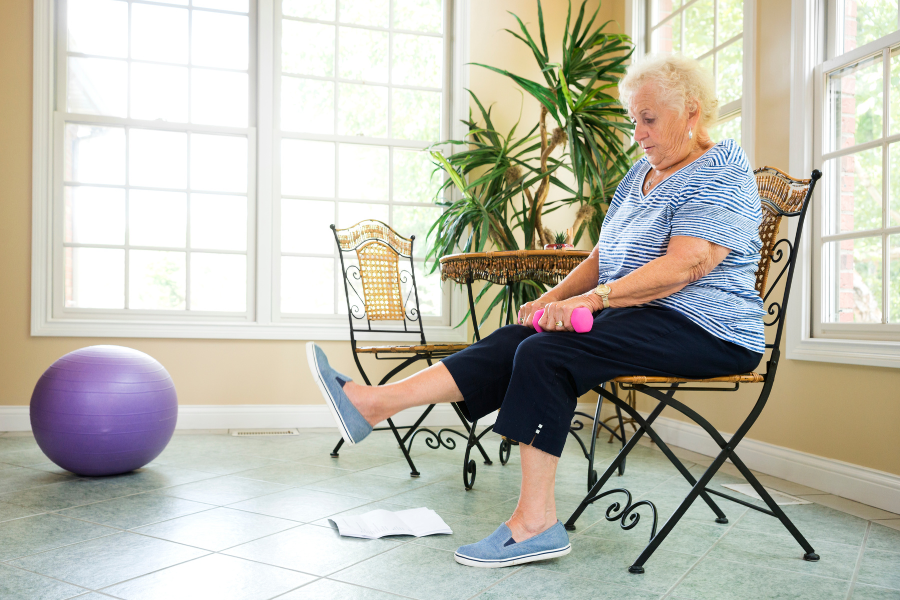 geriatric woman doing seated exercise with hand weight