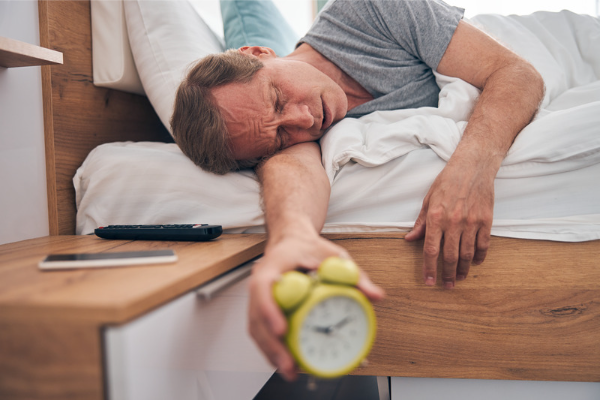 sleeping middle aged man holding an alarm clock