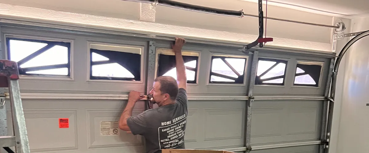 Technician aligning and securing panel of old garage door Technician aligning and securing panel of old garage door