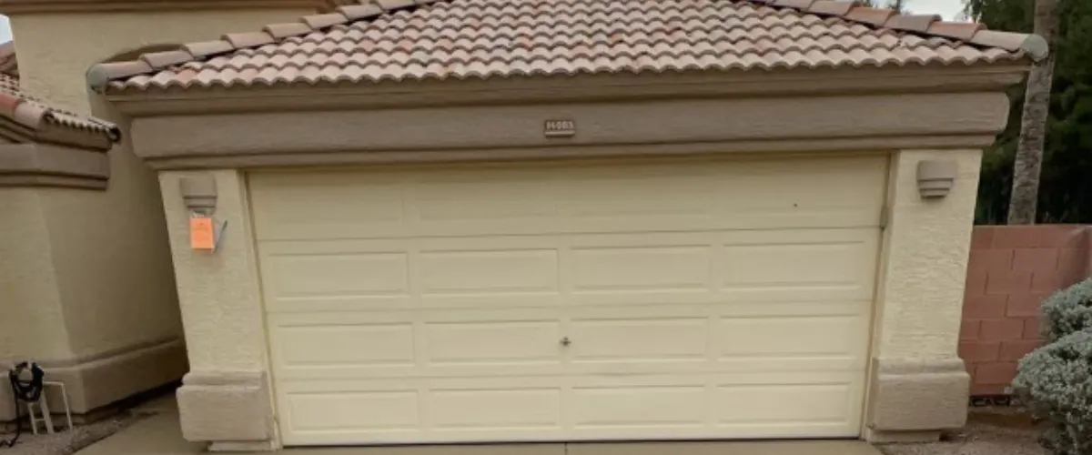 Front view of closed, beige-colored old garage door Front view of closed, beige-colored old garage door