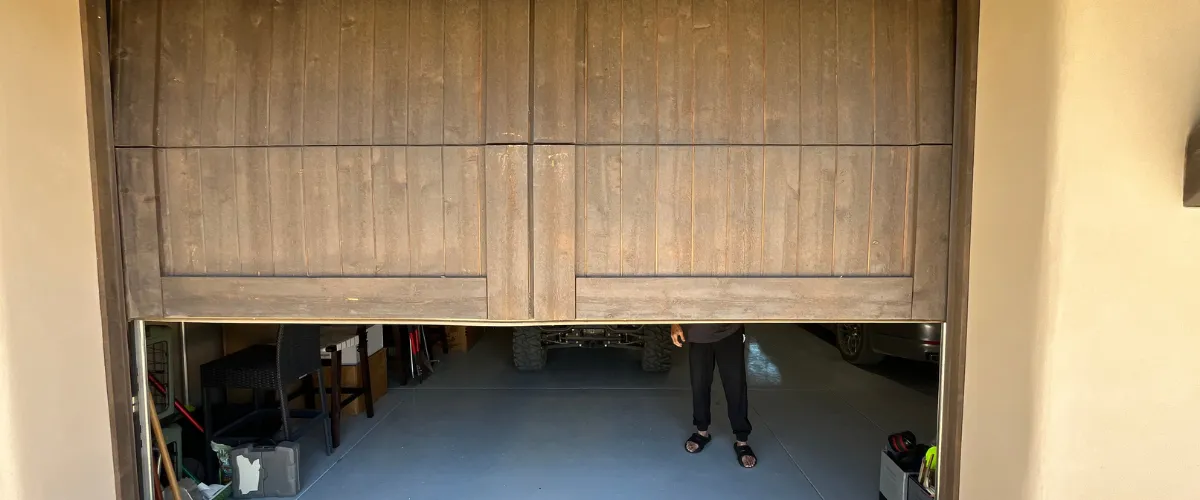Rustic wooden garage door partially opened revealing interior and vehicle Rustic wooden garage door partially opened revealing interior and vehicle