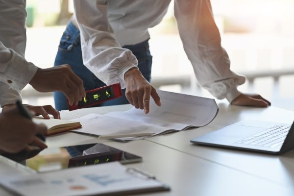 Contractors reviewing blueprints with tools and laptop, planning a remodeling
