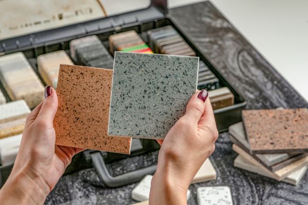 Hands holding bathroom tile samples in different colors