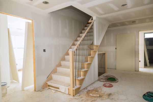 Interior home under construction with unfinished drywall and a wooden staircase installation