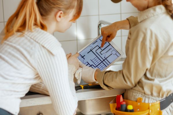 Contractor showing a homeowner a digital floor plan on a tablet during a home renovation consultation.