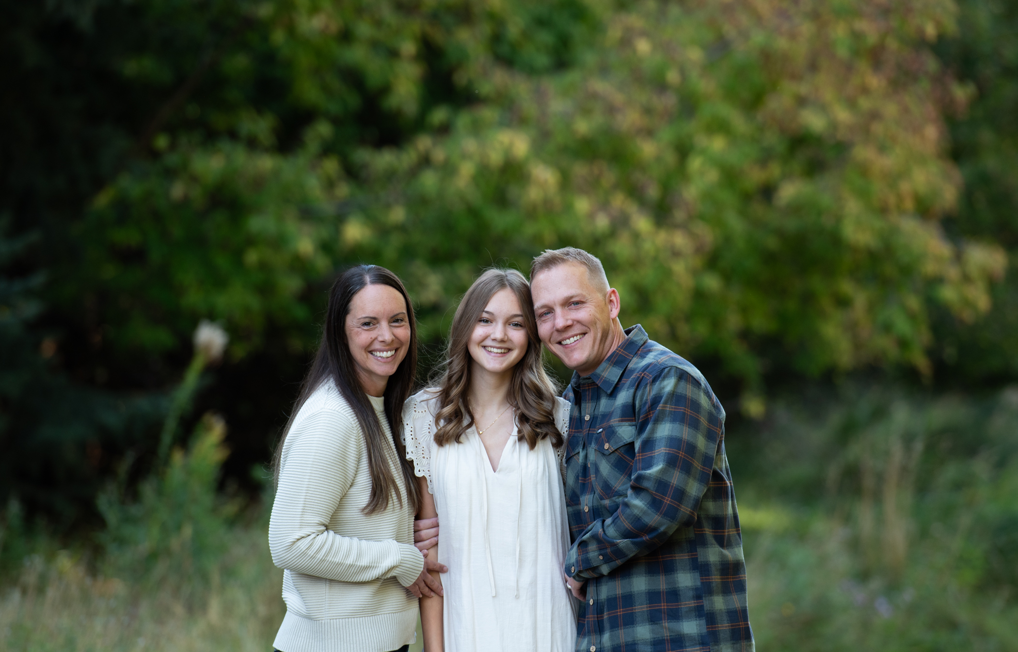 Family with mom, dad and child smiling and hugging at Kathryn Alberson Park in Boise Idaho