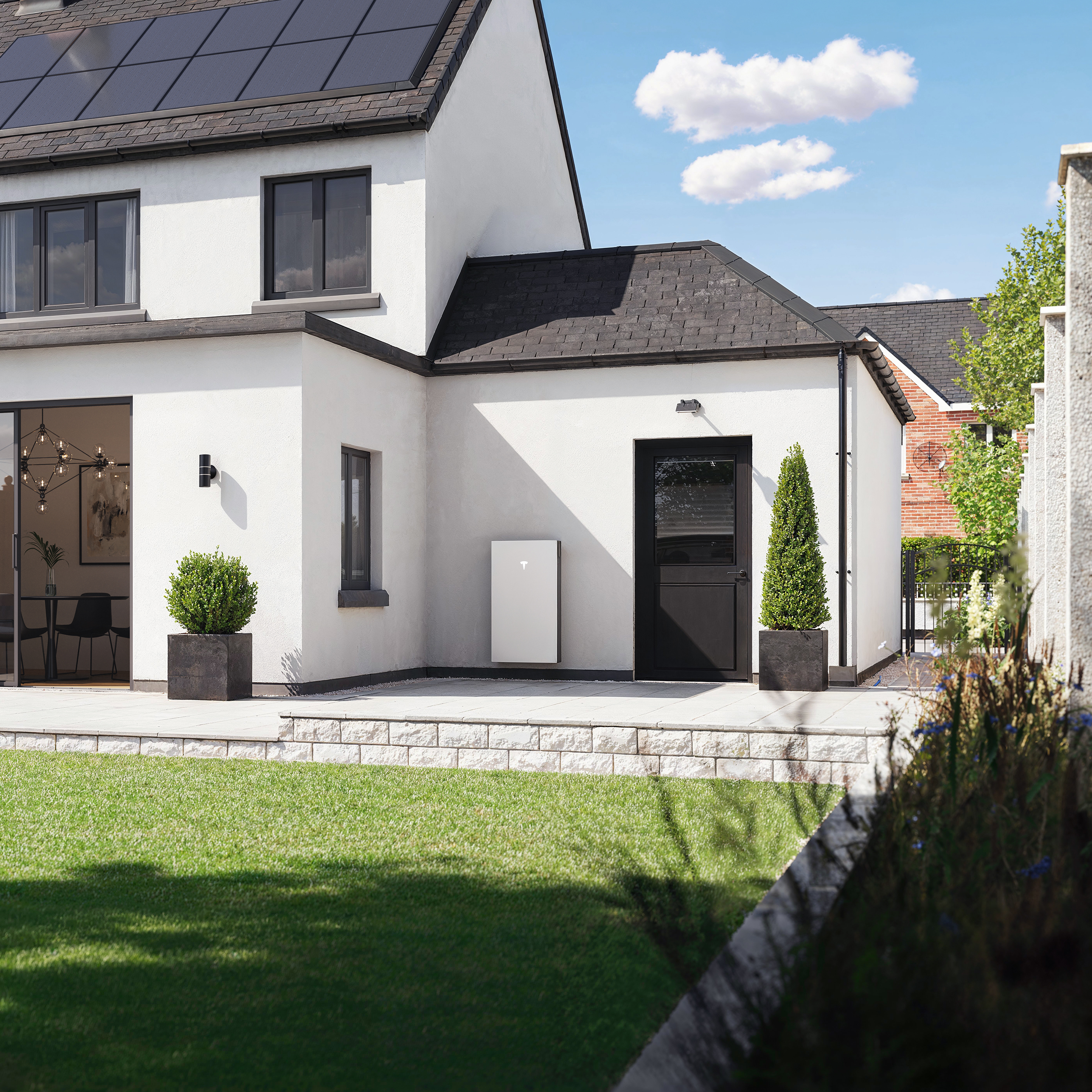 Photo image of a UK home in Nottingham with modern solar panels on the roof and a sleek, wall-mounted home battery unit on the side wall, driveway visible.