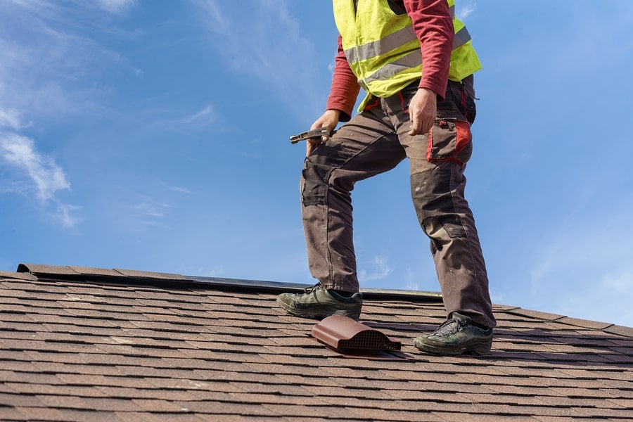 A roofing expert from Masterpiece Roofing in Holliston, MA performing a detailed roof inspection.