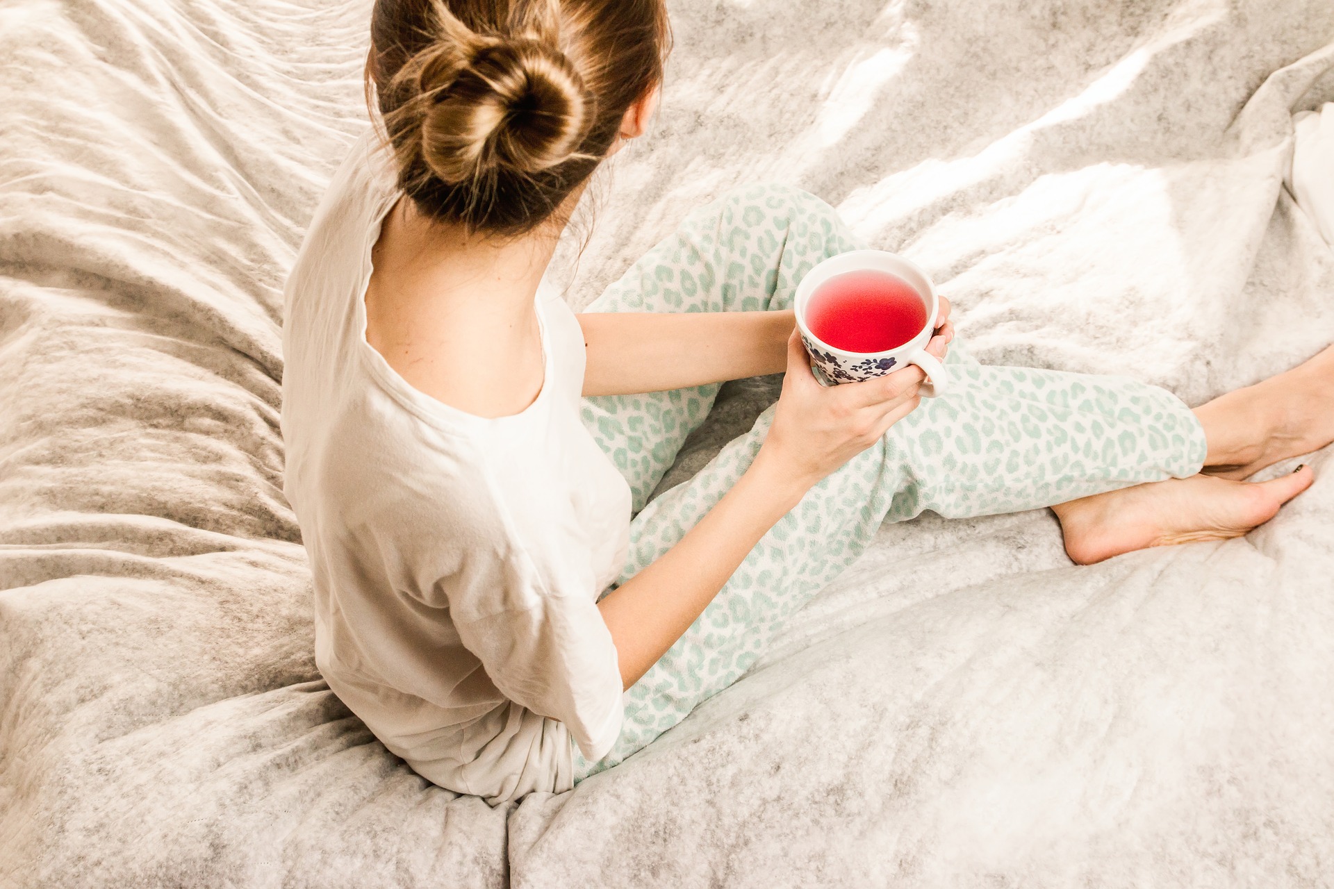 woman sitting on bed with coffee