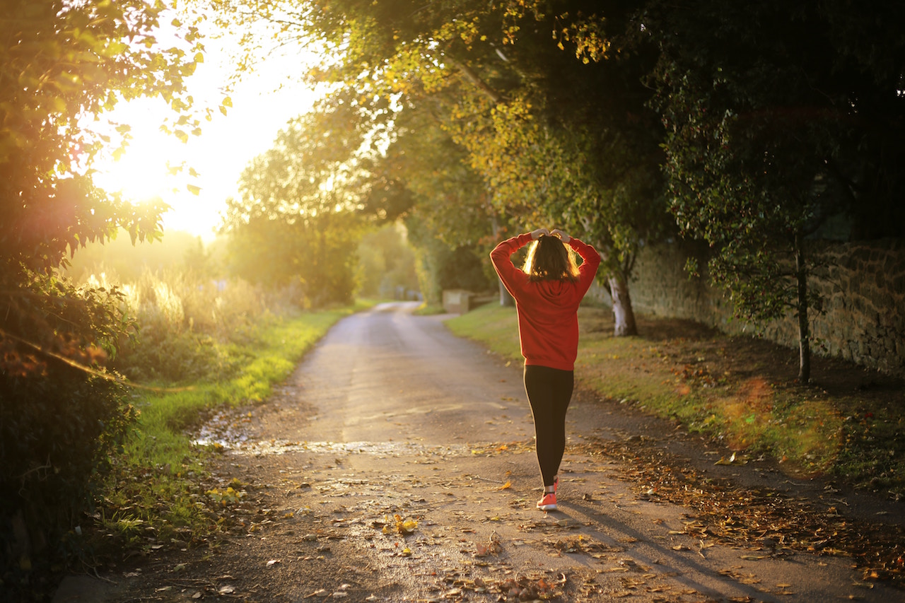 woman walking down a dirt road with the sun shining on her