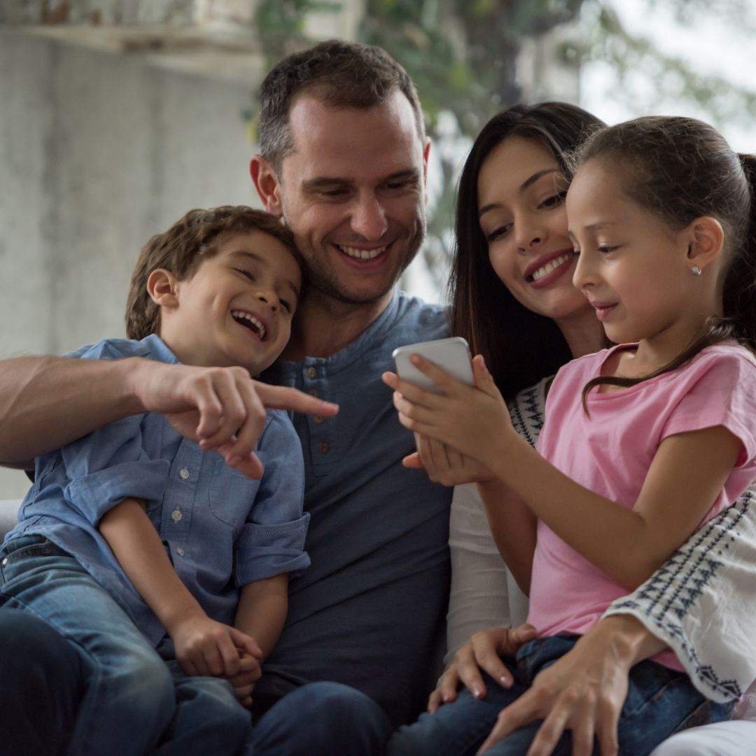 A family gathered at a memorial table listening to a personalized voice message prepared through an AI memorial service.