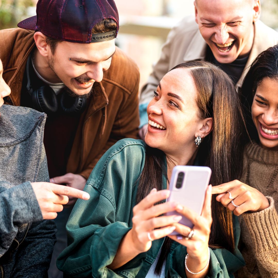 A diverse group of people using smartphones with AI grief apps, symbolizing rising adoption rates in 2025.