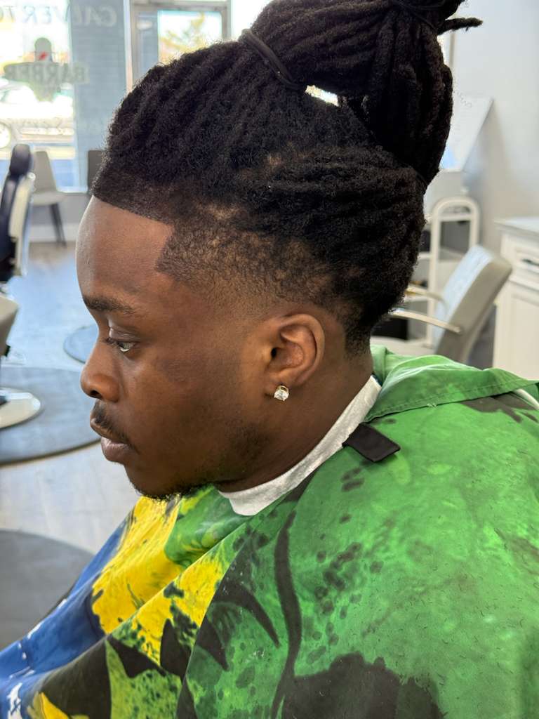 Top-down image of barber tools: scissors, comb, straight razor, and styling cream on wooden tray, styled flat-lay, warm tones.