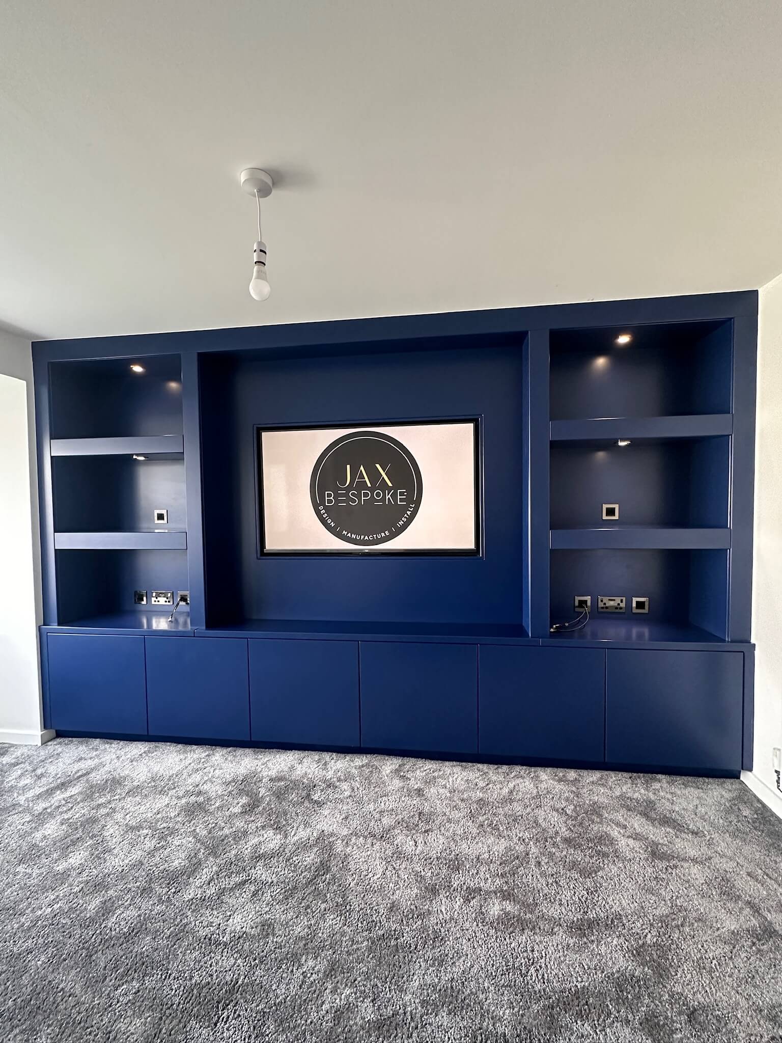 Custom dark blue media wall with integrated storage and floating shelves, crafted by JAX Bespoke installed in Wakefield Custom dark blue media wall with integrated storage and floating shelves, crafted by JAX Bespoke installed in Wakefield