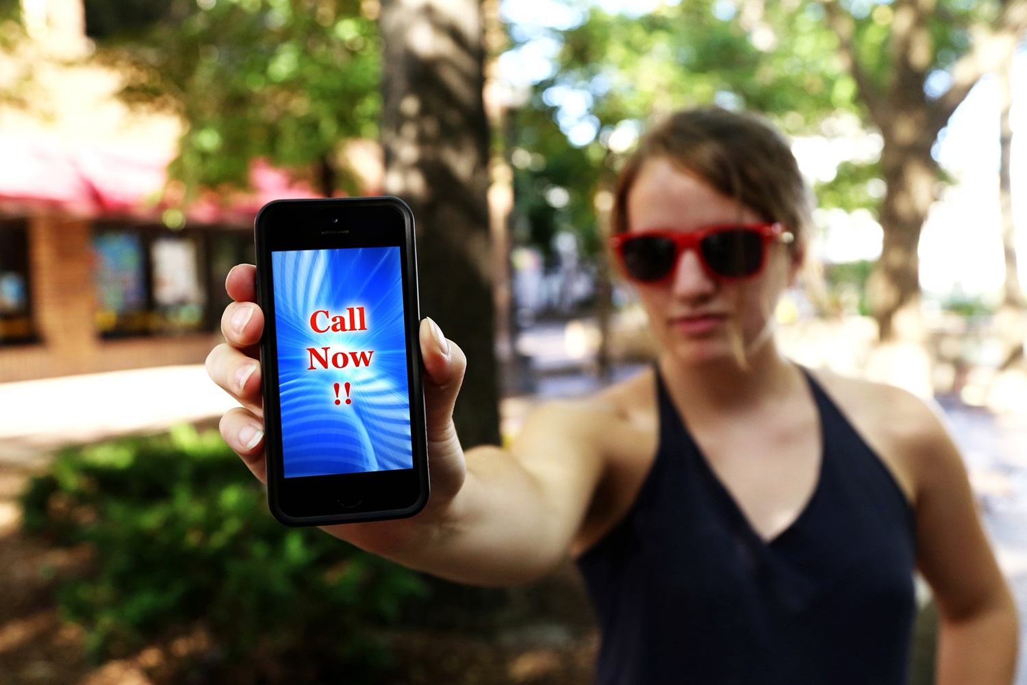 a woman holding a phone that says 'Call Now'