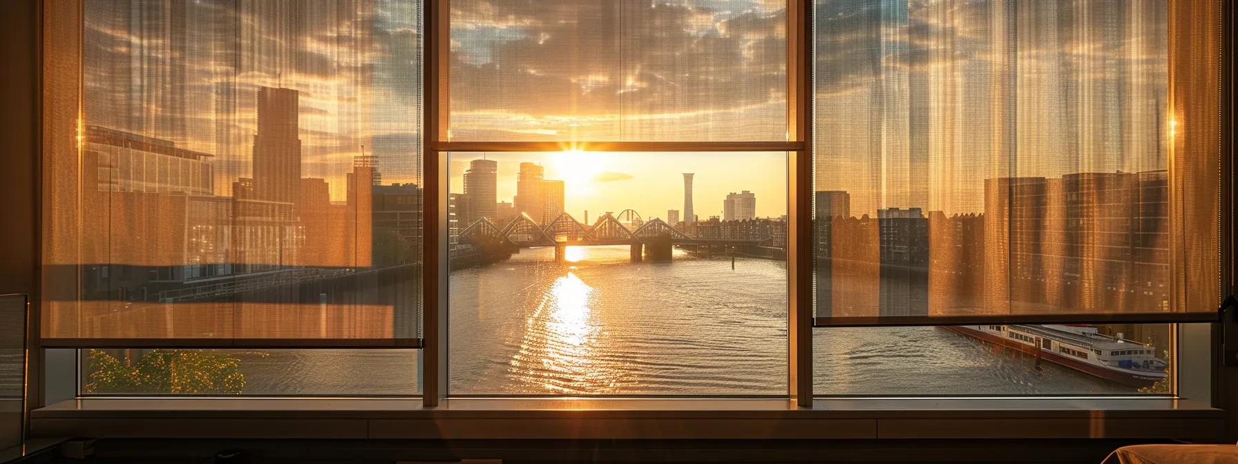 View of a cityscape at sunset through modern, semi-transparent window blinds, filtering the warm, golden light into the room. The blinds allow for partial visibility of buildings, a bridge, and a river below, creating a serene ambiance with reflections on the water and a cozy, soft glow indoors. View of a cityscape at sunset through modern, semi-transparent window blinds, filtering the warm, golden light into the room. The blinds allow for partial visibility of buildings, a bridge, and a river below, creating a serene ambiance with reflections on the water and a cozy, soft glow indoors.