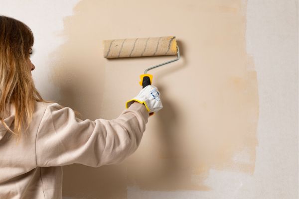 woman painting a wall using paint roll woman painting a wall using paint roll