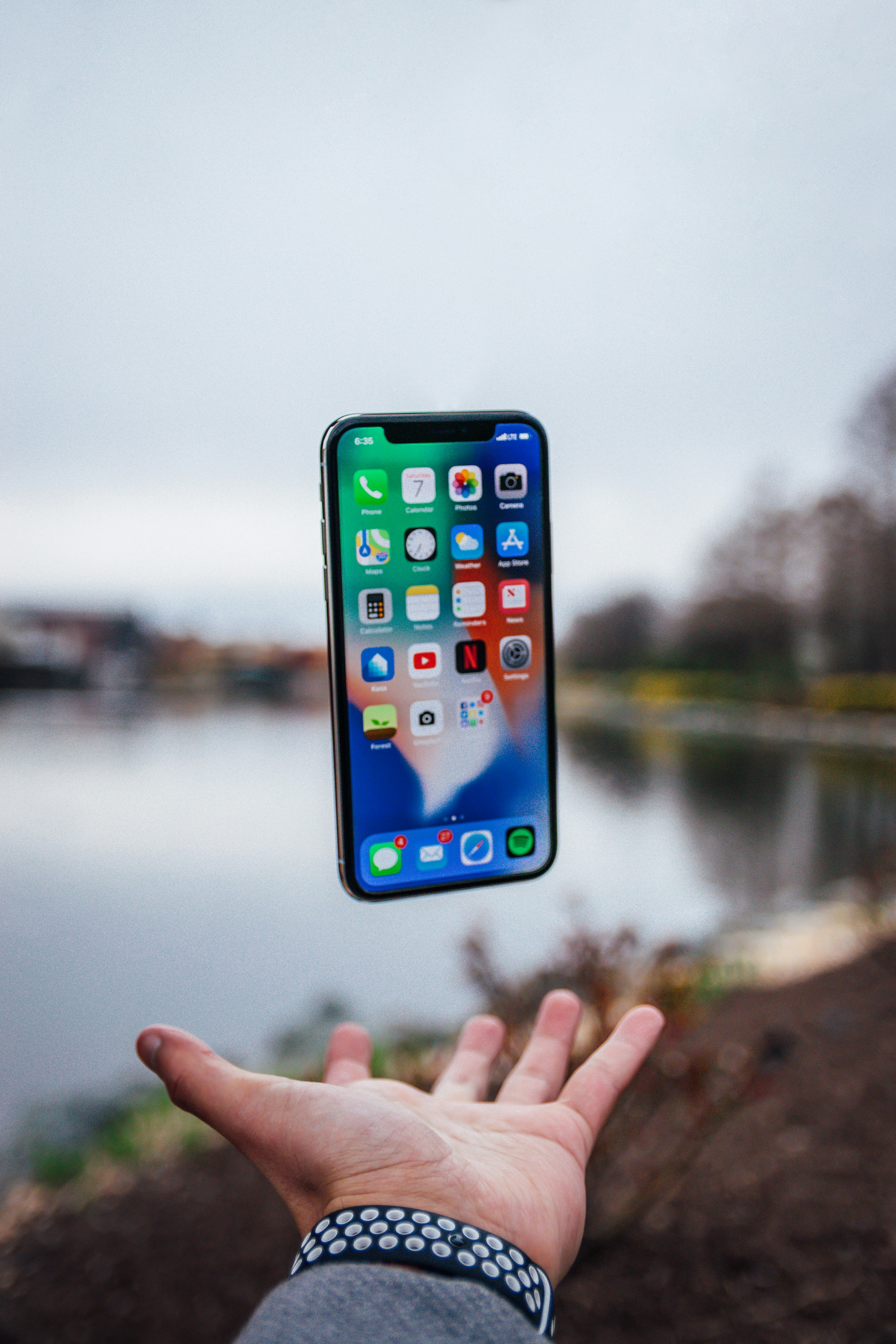 A cellphone floats in the air near a man's hand.