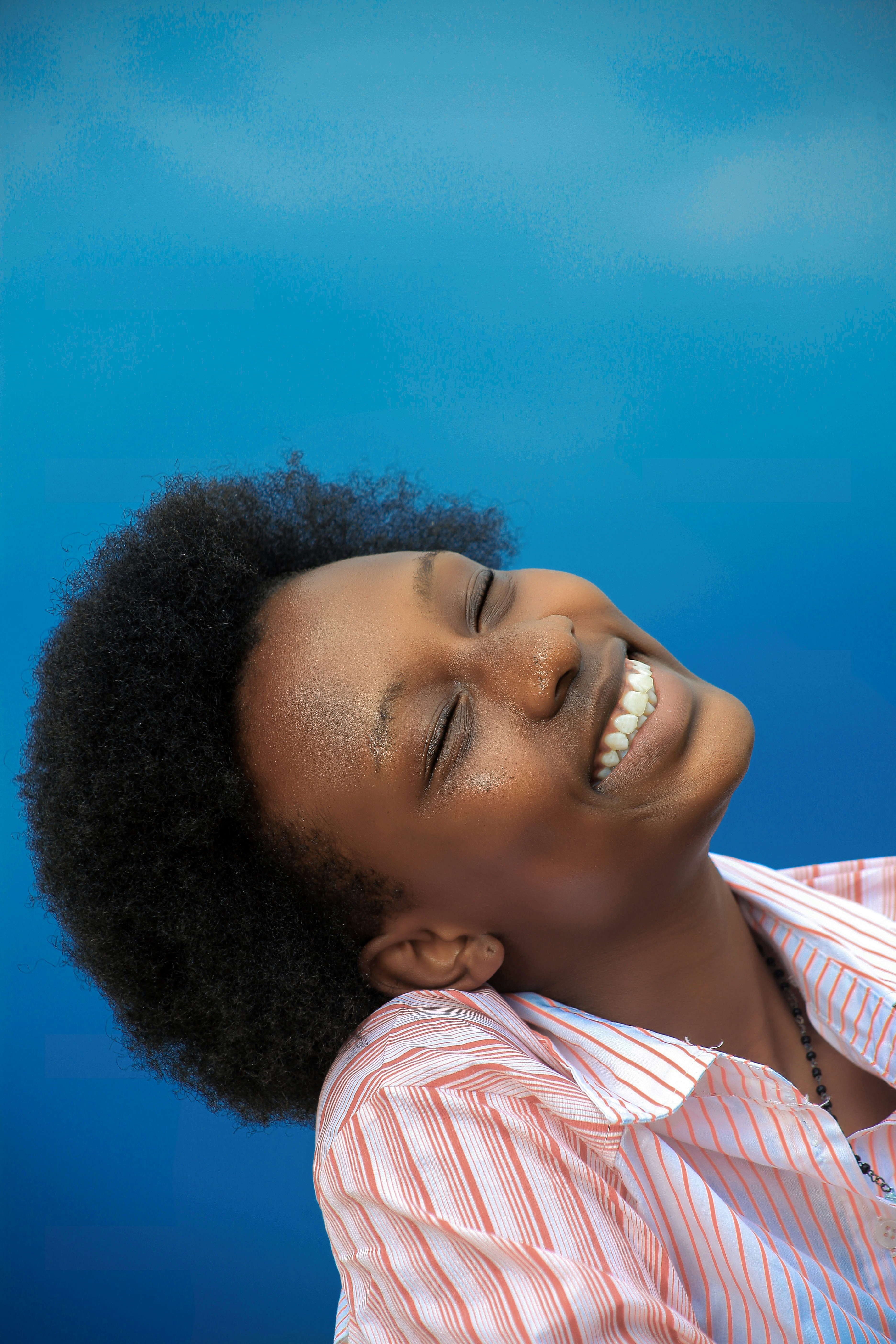 A black woman is smiling, her face lifted towards the sky