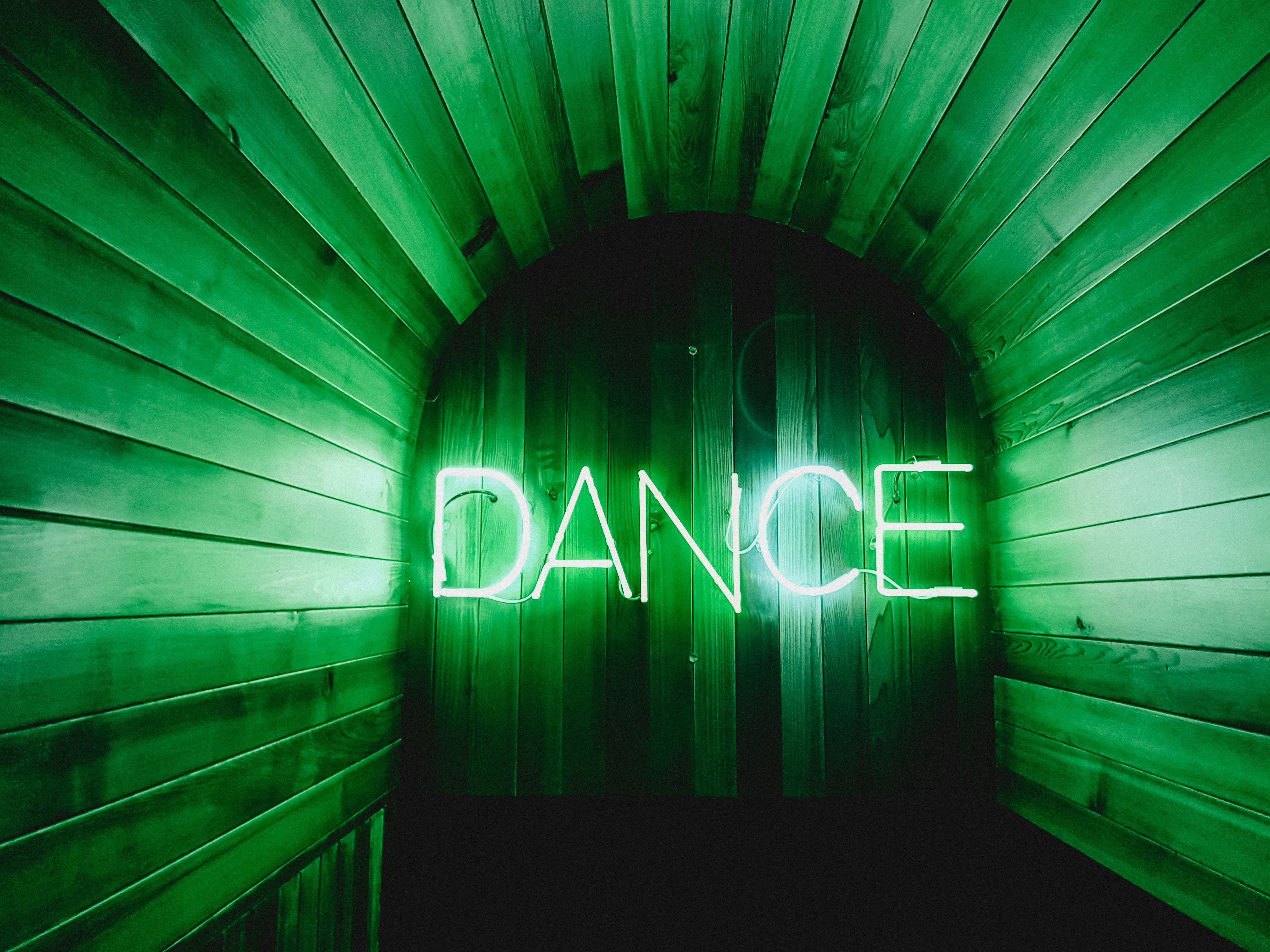 A green neon sign reads Dance