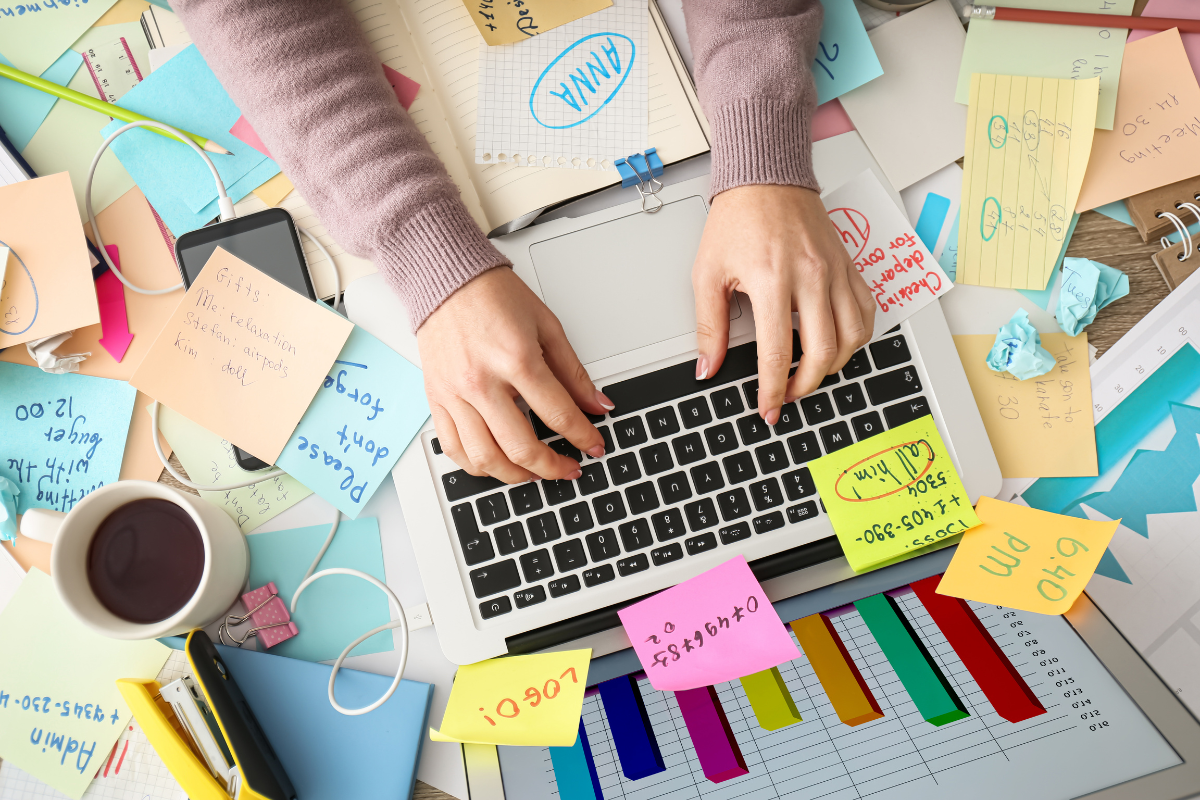 photo of a woman working at her desk covered in papers and sticky notes