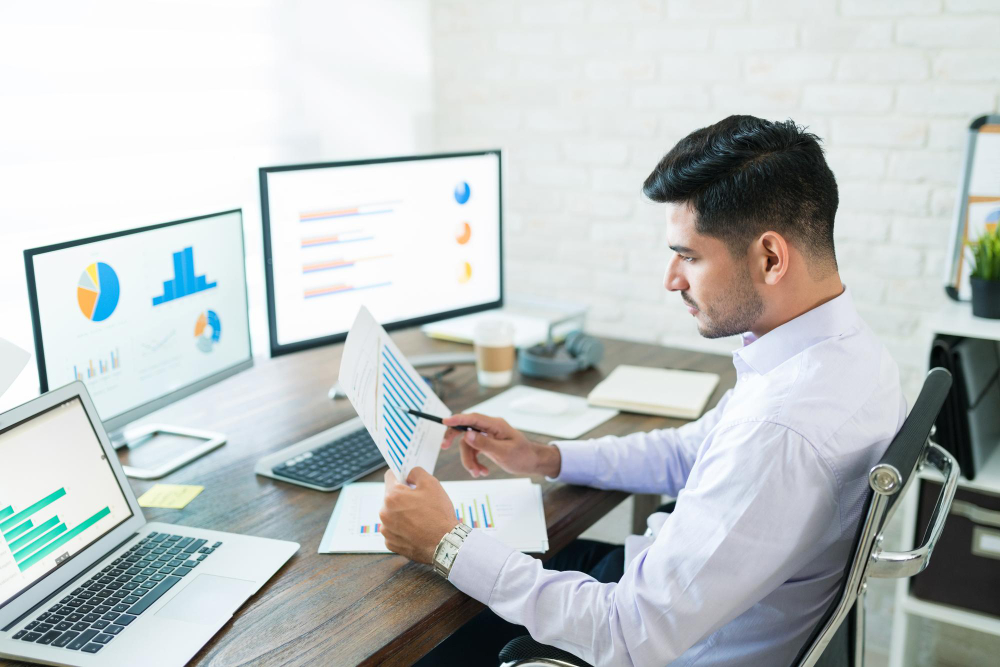 Construction manager analyzing job costing and performance data on a digital dashboard to reduce cost drains and improve efficiency Construction manager analyzing job costing and performance data on a digital dashboard to reduce cost drains and improve efficiency